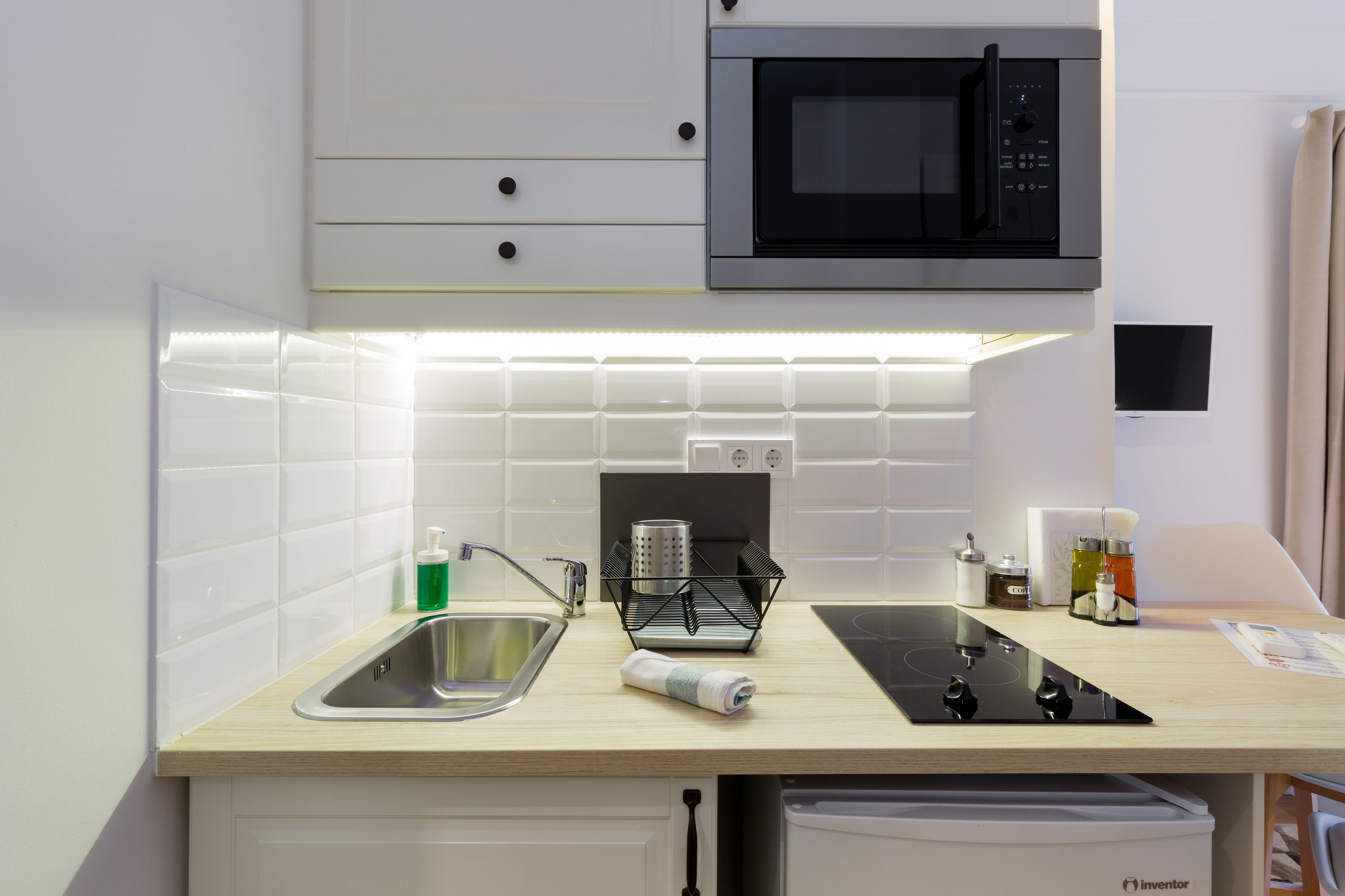 Cozinha moderna com micro-ondas, pia e escorredor de louça.