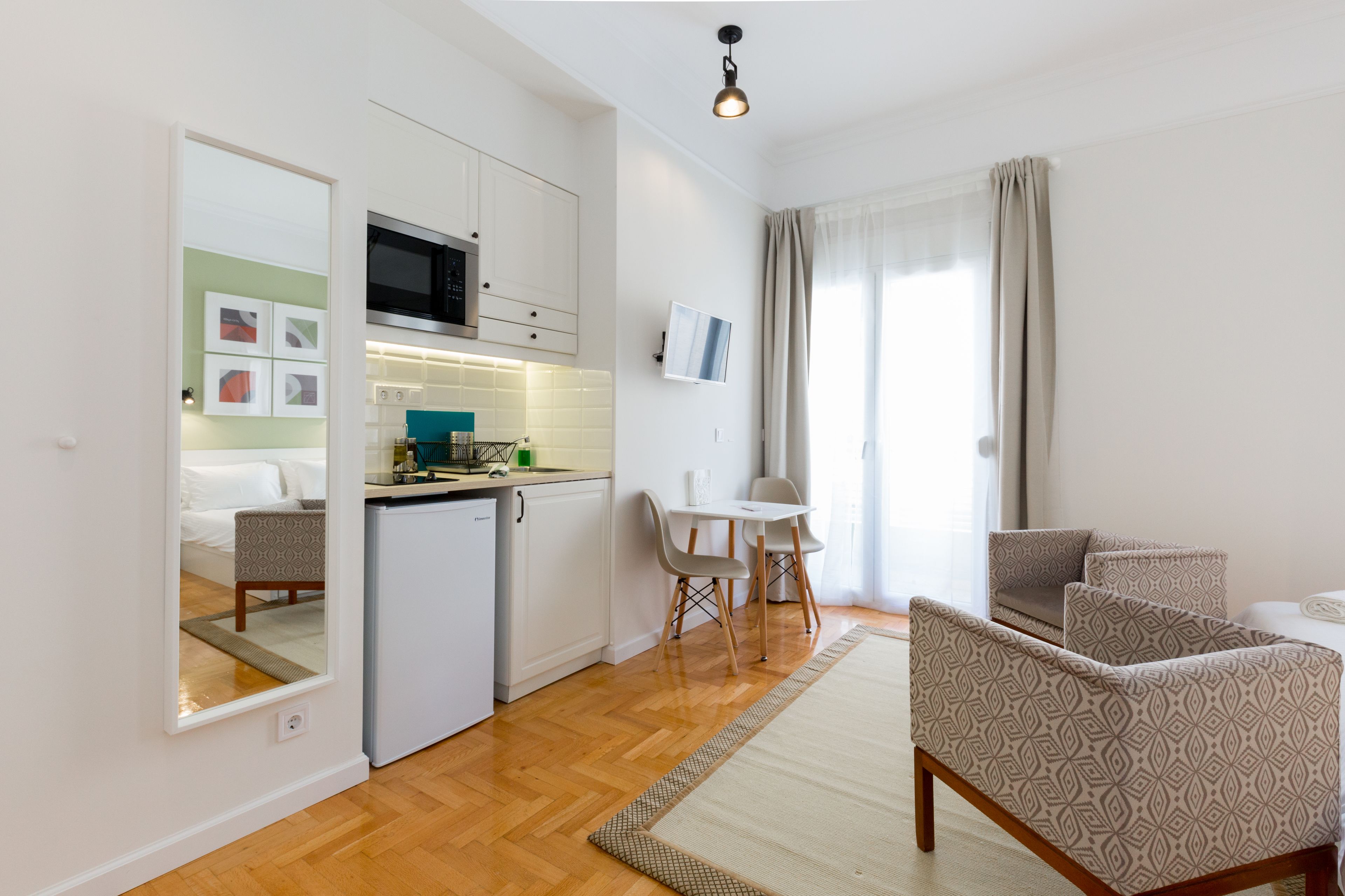 Un espacio habitable compacto con kitchenette, comedor y zona de estar con sofás estampados.