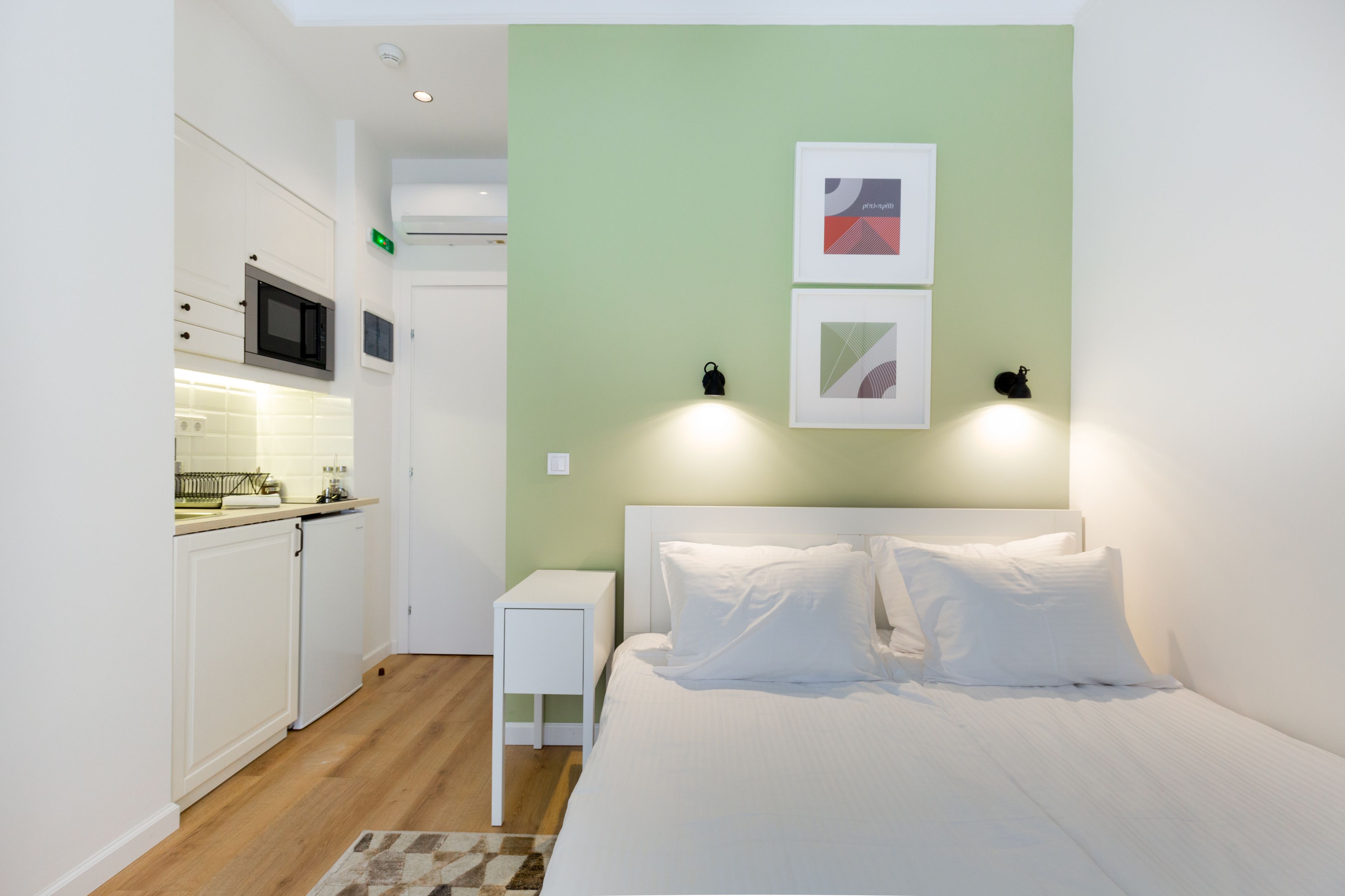 Une chambre à coucher de taille réduite, comprenant un lit, des tables de chevet et une petite kitchenette.