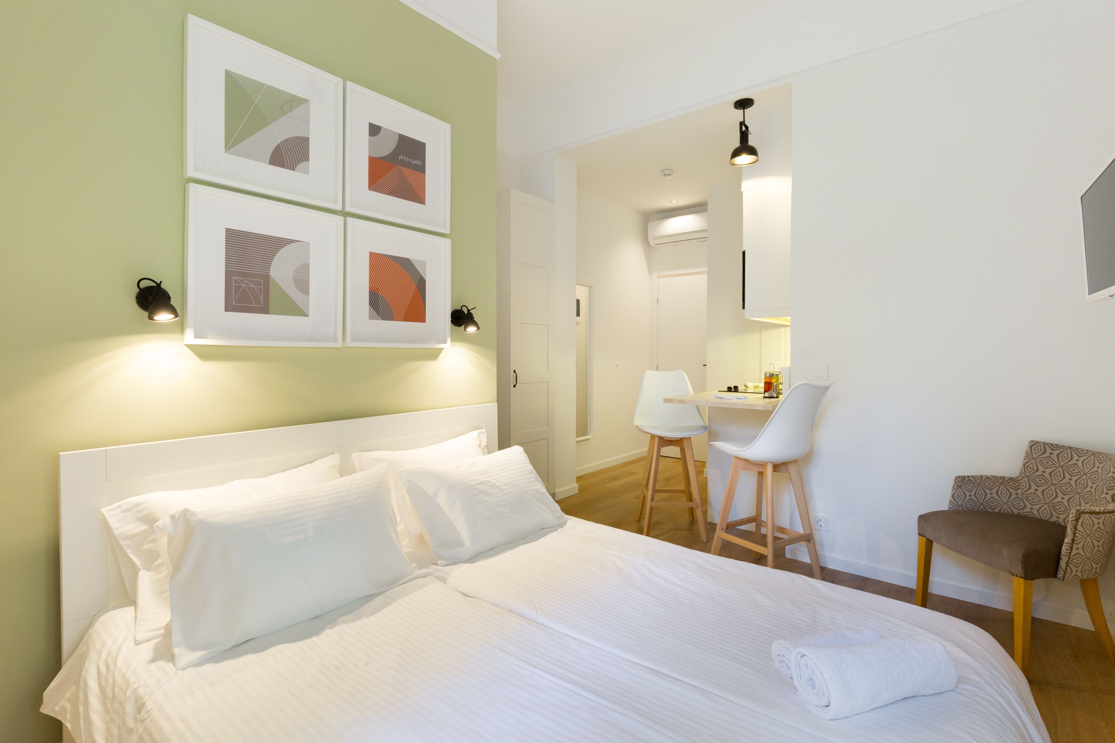 A neatly arranged hotel room with a large bed, a desk, and a chair.