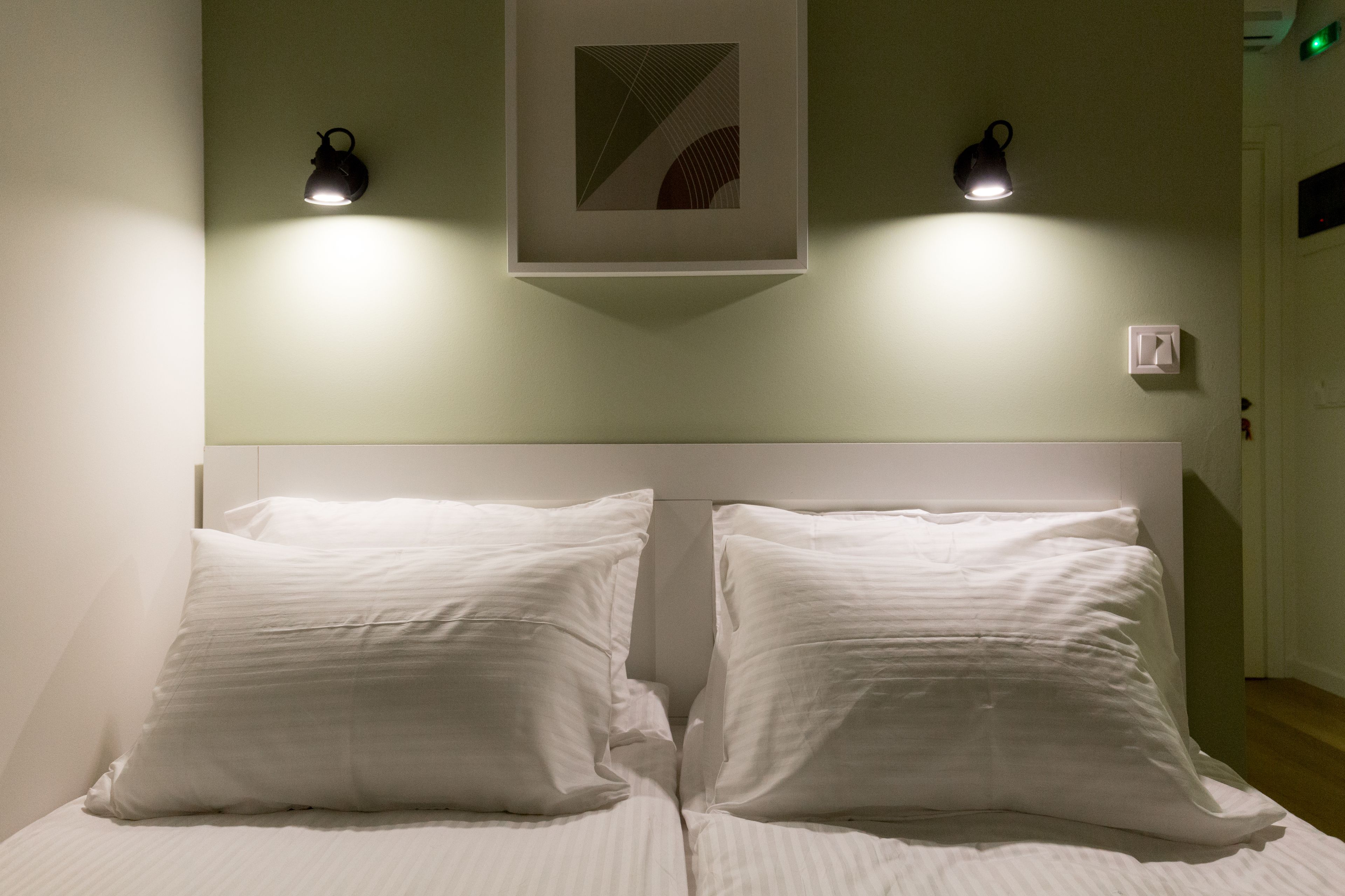 A bed with white linens and two bedside lamps.