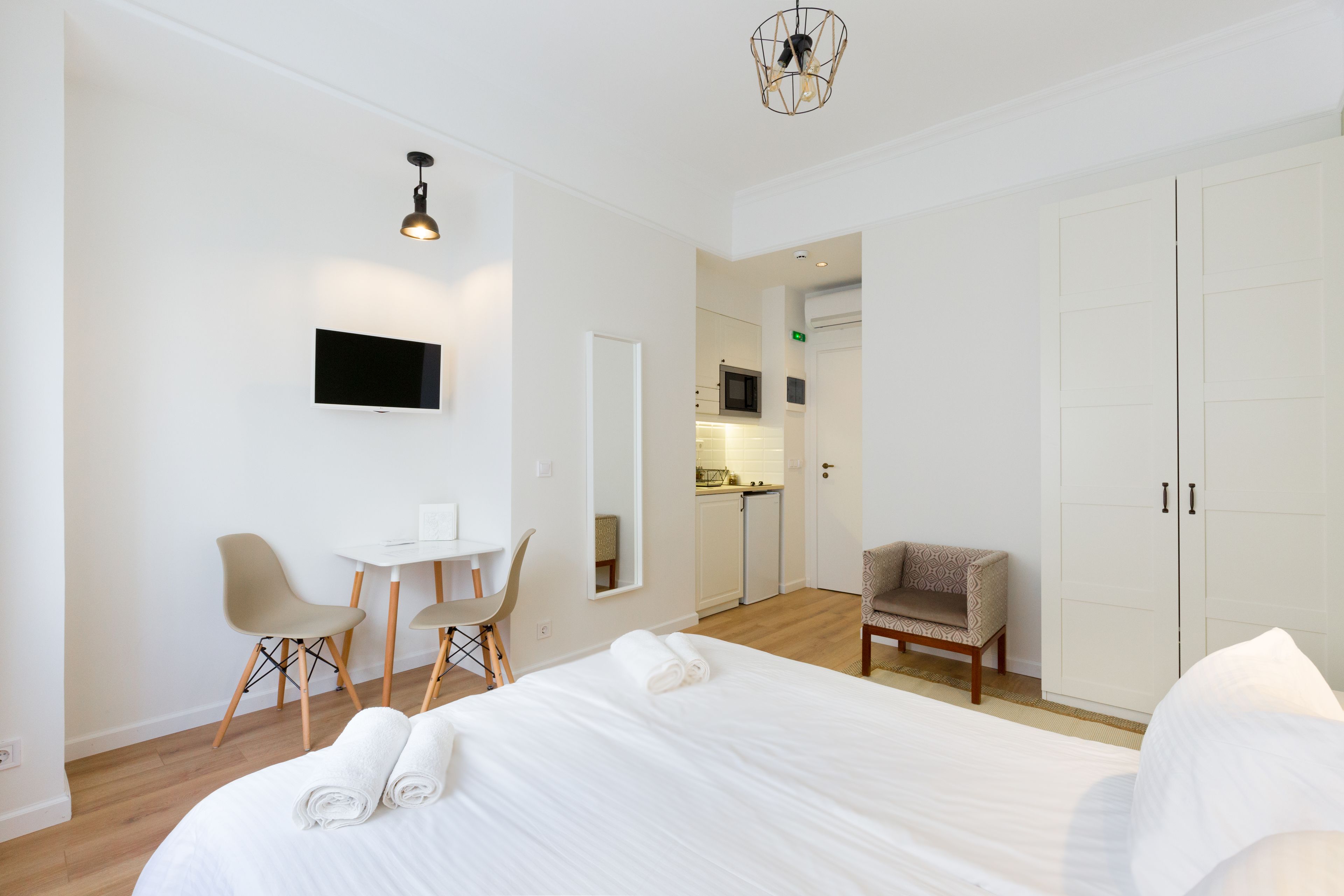 Camera d'albergo con un letto grande, una scrivania, due sedie, un armadio e un angolo cottura sullo sfondo.