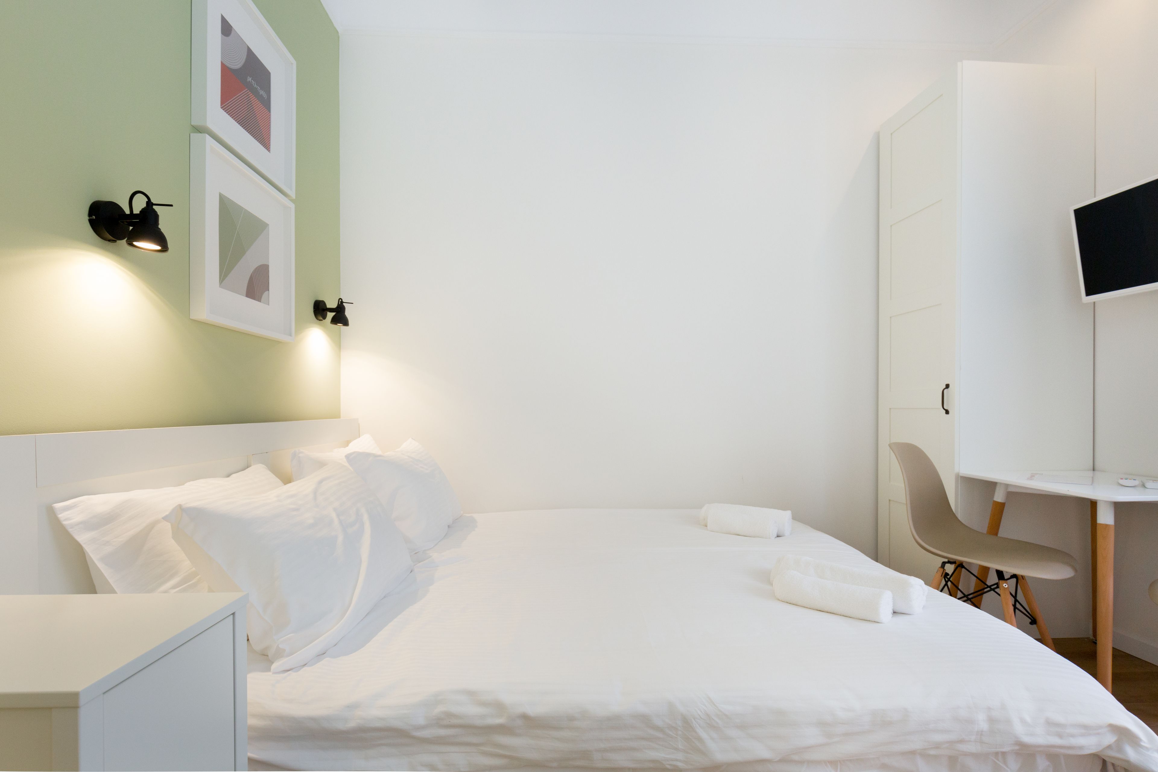 A modern hotel room with a neatly made bed, a desk, and a chair.