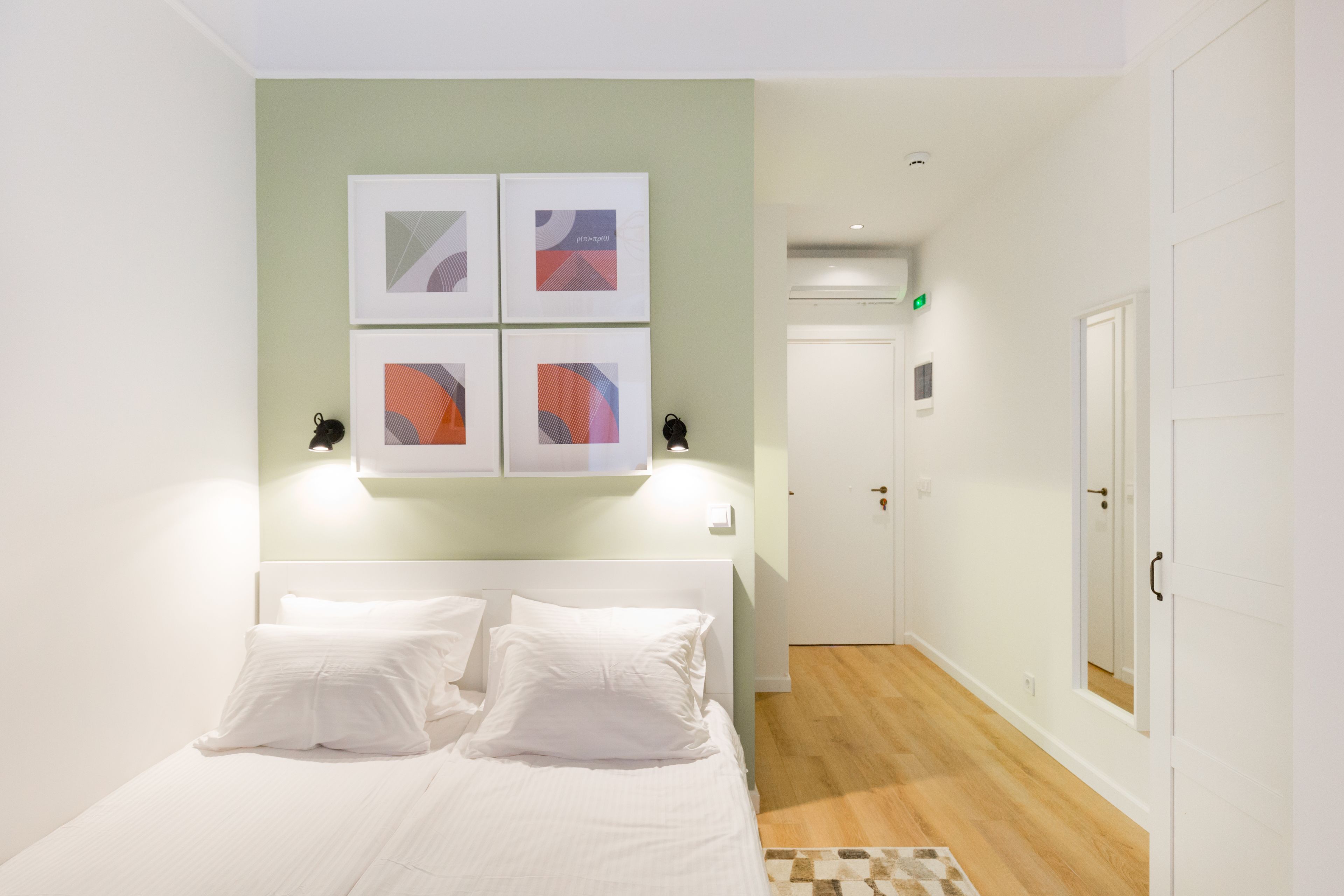 Una habitación de hotel con una cama, una obra de arte en la pared, una puerta y un pasillo.