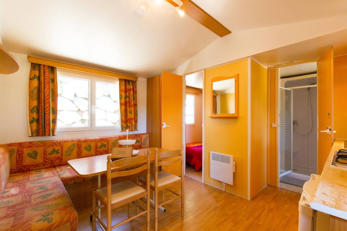 Habitación pequeña con un banco de madera, una mesa y zona de ducha.