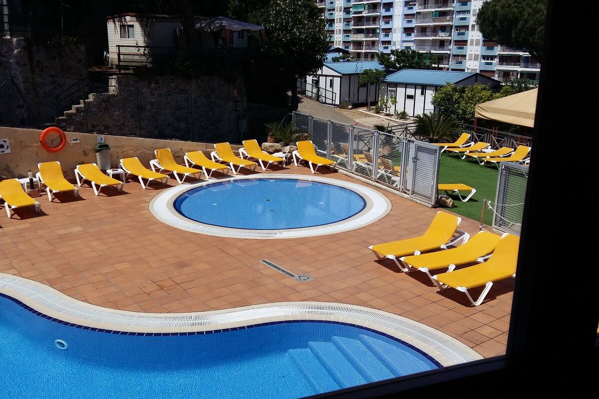 Zona de piscina con tumbonas amarillas y una piscina circular.