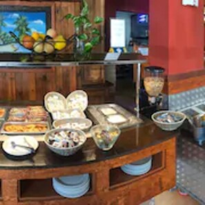A buffet area with various food items and a fruit display.