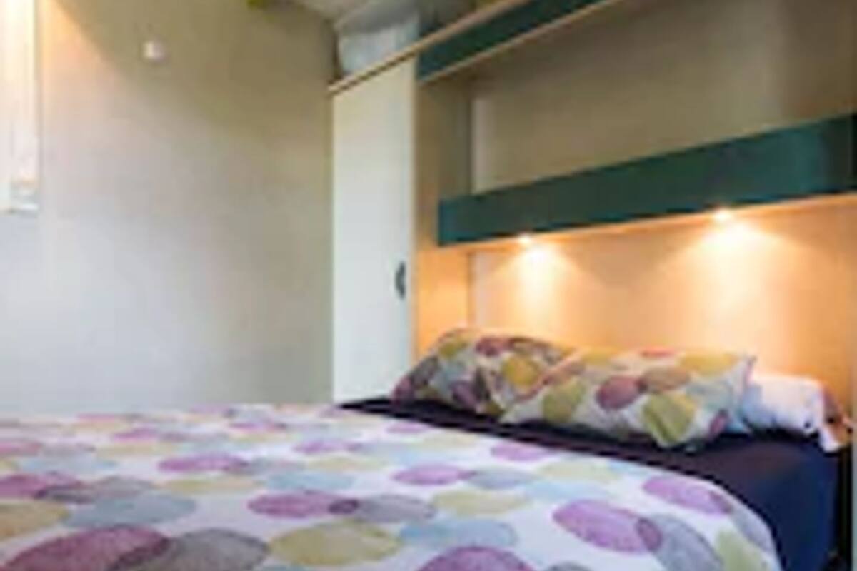Un dormitorio con cama, almohadas y cabecera.