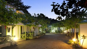 A row of single-story buildings with open porches and a dirt ground. - Camping El Far (Calella)