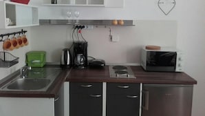 A compact kitchen with a sink, stove, microwave, and a small countertop area. - Apartment Jasenka (Pag)