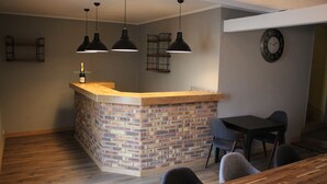 A kitchen with a brick accent wall, pendant lighting, a wooden counter, and a clock on the wall. - La Part Des Anges (Mardeuil)