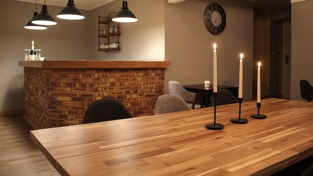 A wooden dining table with candles, a brick wall, and pendant lights. - La Part Des Anges (Mardeuil)