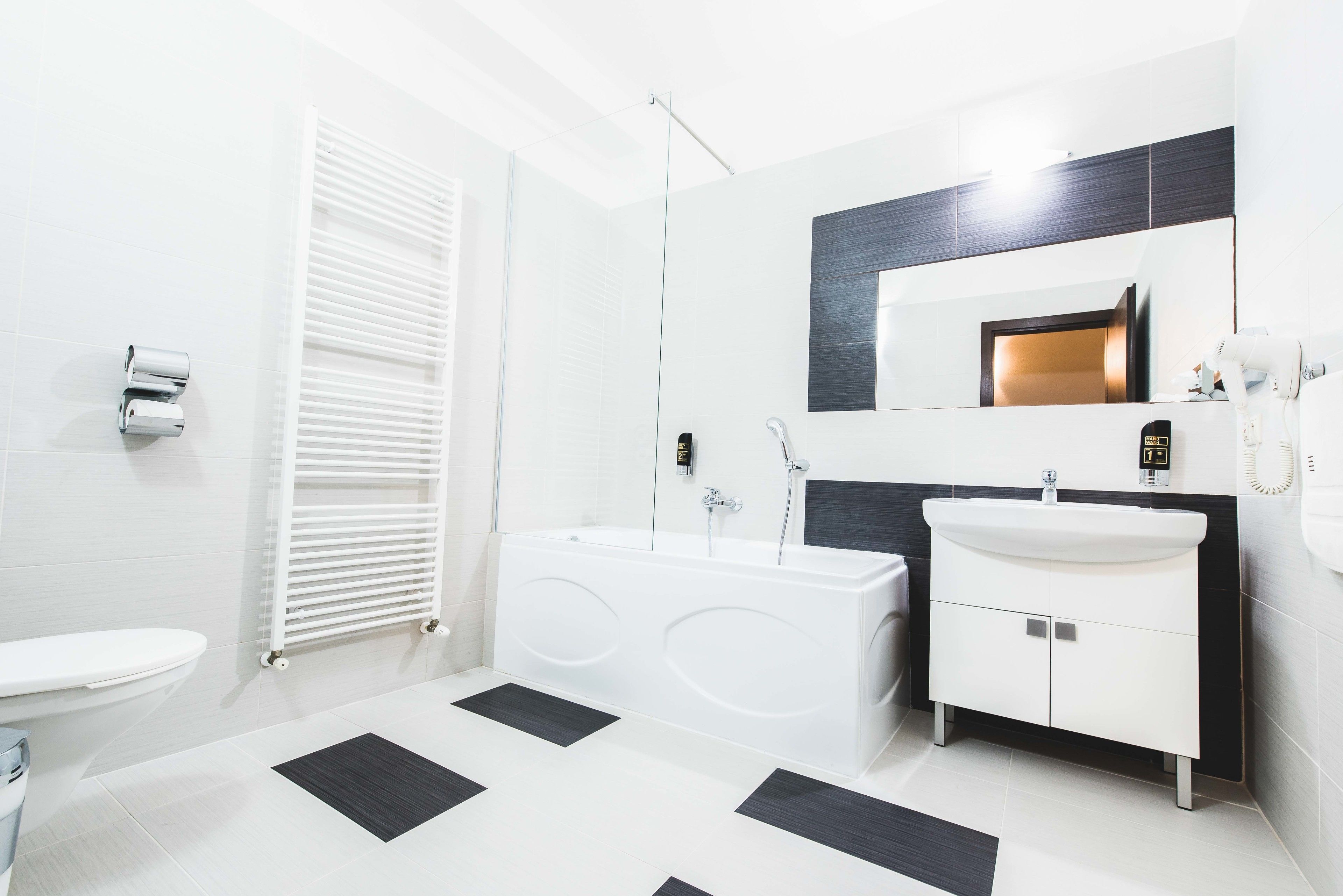 Une salle de bain moderne avec des toilettes blanches, une baignoire, un lavabo et un miroir.