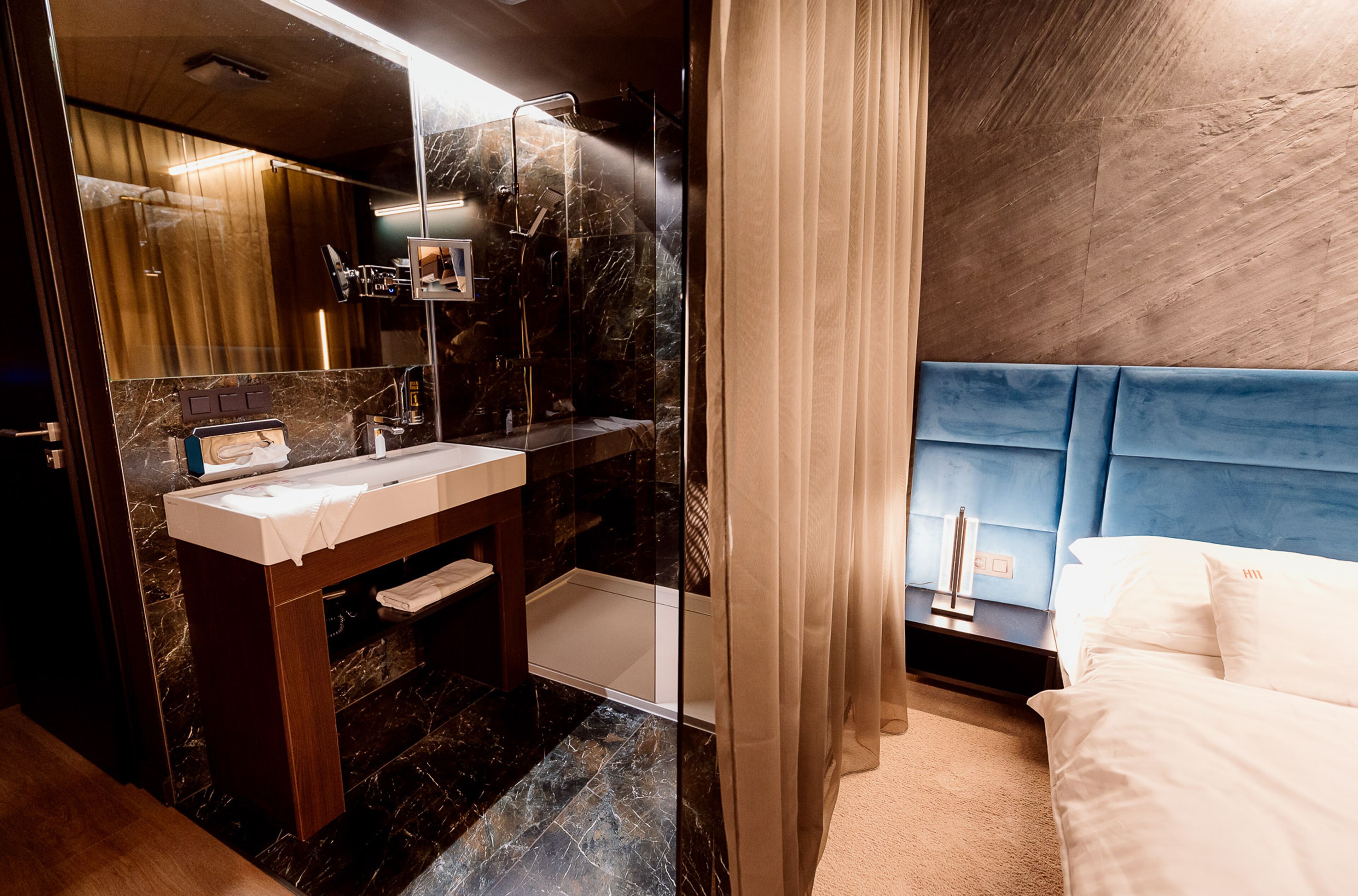 Une salle de bain moderne avec un meuble-lavabo en marbre, un grand miroir et un espace douche.