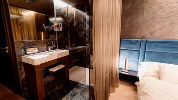 Une salle de bain moderne avec un meuble-lavabo en marbre, un grand miroir et un espace douche.