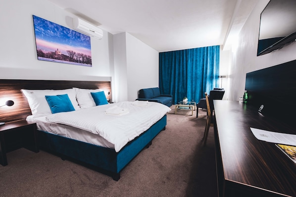 A hotel room with a large bed, a desk, a chair, a TV, and a painting on the wall. - BOUTIQUE HOTEL11 with rooftop SPA (Nitra)