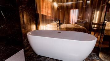 Un baño moderno con una bañera independiente, suelo de mármol y un espejo grande.