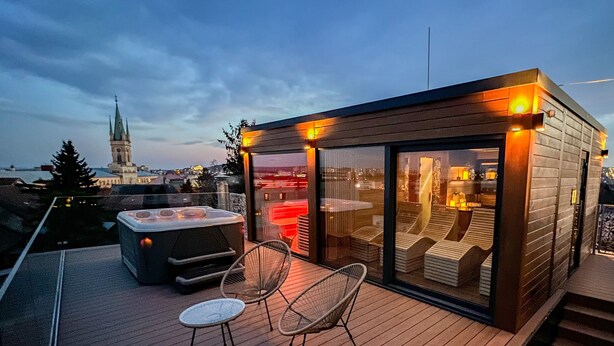 A modern rooftop terrace with a hot tub, lounge chairs, and a glass-enclosed seating area. - BOUTIQUE HOTEL11 with rooftop SPA (Nitra)