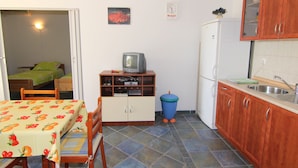 A compact kitchen with a dining table, a small TV, and a refrigerator.