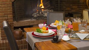 A dining table set with plates, glasses, and a pitcher of beer, with a brick fireplace in the background. - Les Jardins de Beauve (Héricourt-sur-Thérain)
