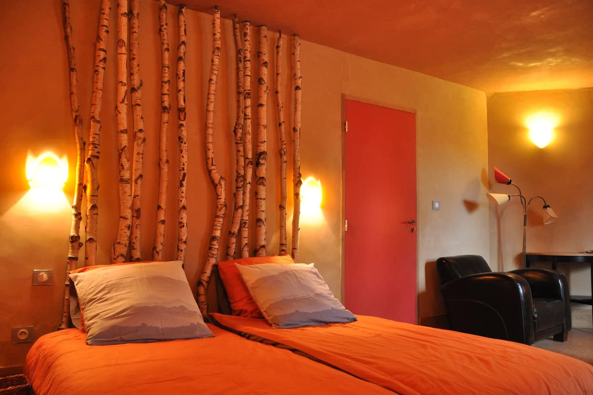 Une chambre d’hôtel avec un lit, une chaise, un bureau et une porte.