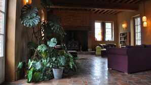 A cozy living room with a brick fireplace, large potted plants, and comfortable seating. - Les Jardins de Beauve (Héricourt-sur-Thérain)