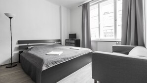 A modern bedroom with a bed, bedside table, lamp, and a view of the city through a window. - Premier Apartment Old Town Hradebni (Prague)