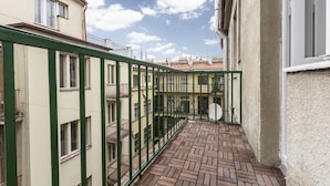 A narrow corridor with a herringbone-patterned floor, bordered by buildings with green railings and multiple windows. - Premier Apartment Old Town Hradebni (Prague)