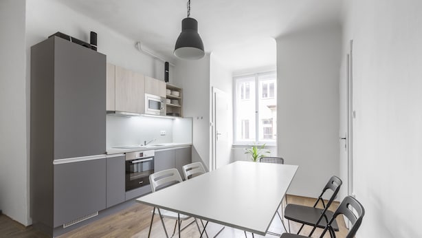 A modern kitchen with a white dining table and chairs, a hanging light fixture, and a view of the outside. - Premier Apartment Old Town Hradebni (Prague)