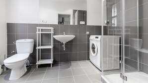 A modern bathroom with a toilet, sink, and washing machine. - Premier Apartment Old Town Hradebni (Prague)