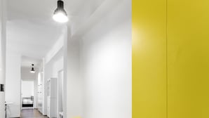A hallway with wooden flooring, white walls, and a yellow accent wall. - Premier Apartment Old Town Hradebni (Prague)