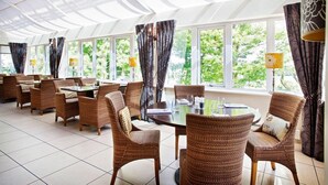 A restaurant with wicker chairs and tables, large windows with curtains, and a ceiling with a geometric pattern. - 315 Bar And Restaurant (Huddersfield)