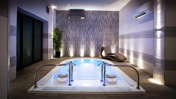 A modern spa area with a rectangular hot tub, a potted plant, and a lounge chair. - 315 Bar And Restaurant (Huddersfield)