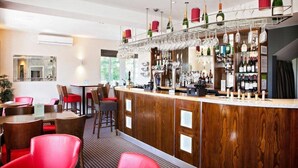 A bar area with a wooden counter, red chairs, and a wine rack with bottles and glasses. - 315 Bar And Restaurant (Huddersfield)