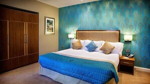 A hotel room with a large bed, a wardrobe, a nightstand with a lamp, and a wall with a peacock feather pattern. - 315 Bar And Restaurant (Huddersfield)