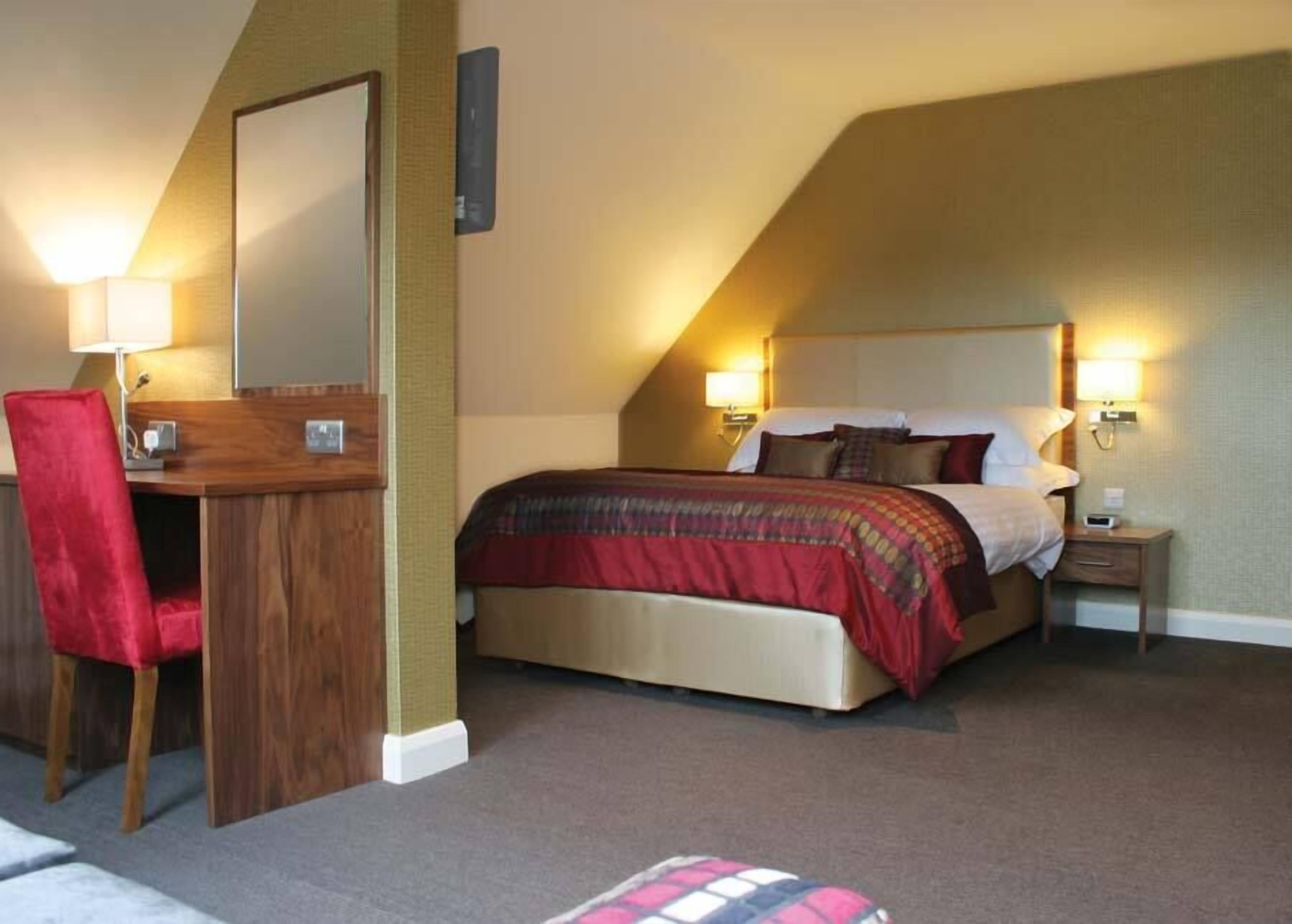 A bedroom with a bed, bedside tables, a desk, and a chair.