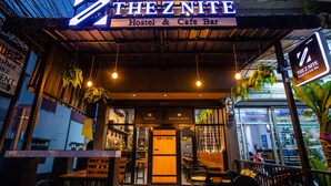 El hostal Z Nite & Cafe Bar con fachada de madera, plantas colgantes y un cartel.