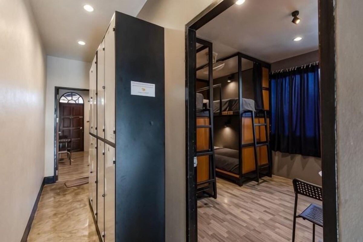 A hotel room with a wardrobe, a bed, a desk, and a chair.