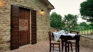 Un edificio de piedra con una puerta de madera y una mesa con sillas en un patio empedrado.