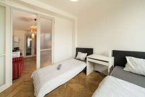 Une chambre d’hôtel moderne avec deux lits, un bureau et un canapé rouge.