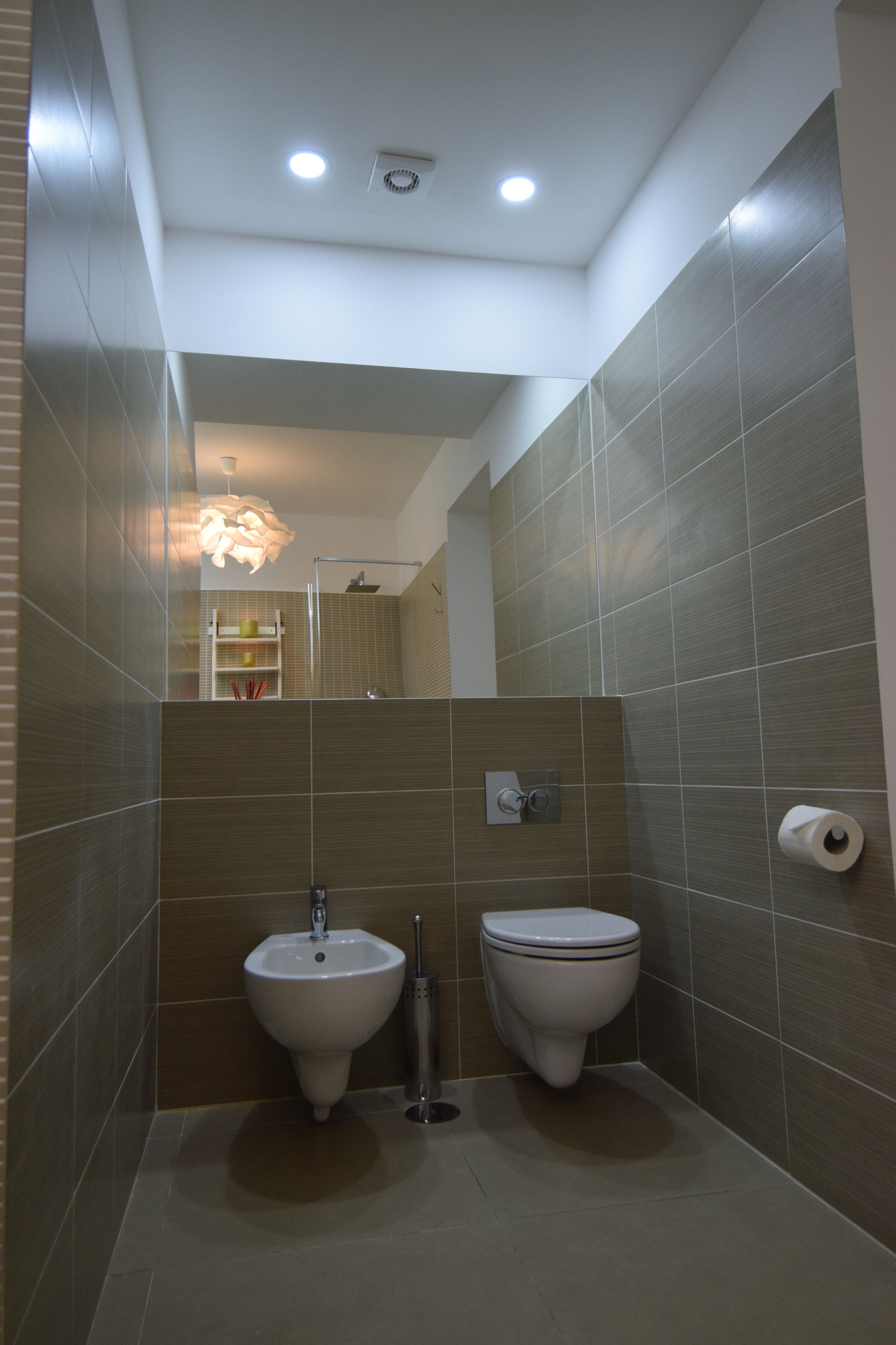 Une salle de bain moderne équipée d’un bidet, de toilettes et d’un miroir.