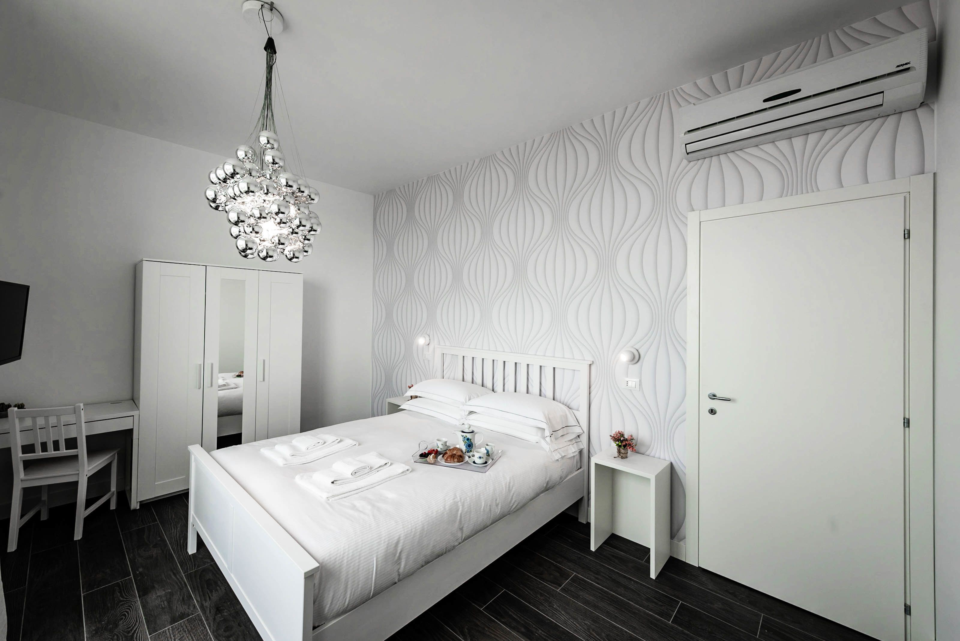 A modern bedroom with a bed, bedside tables, a desk, and a wardrobe.