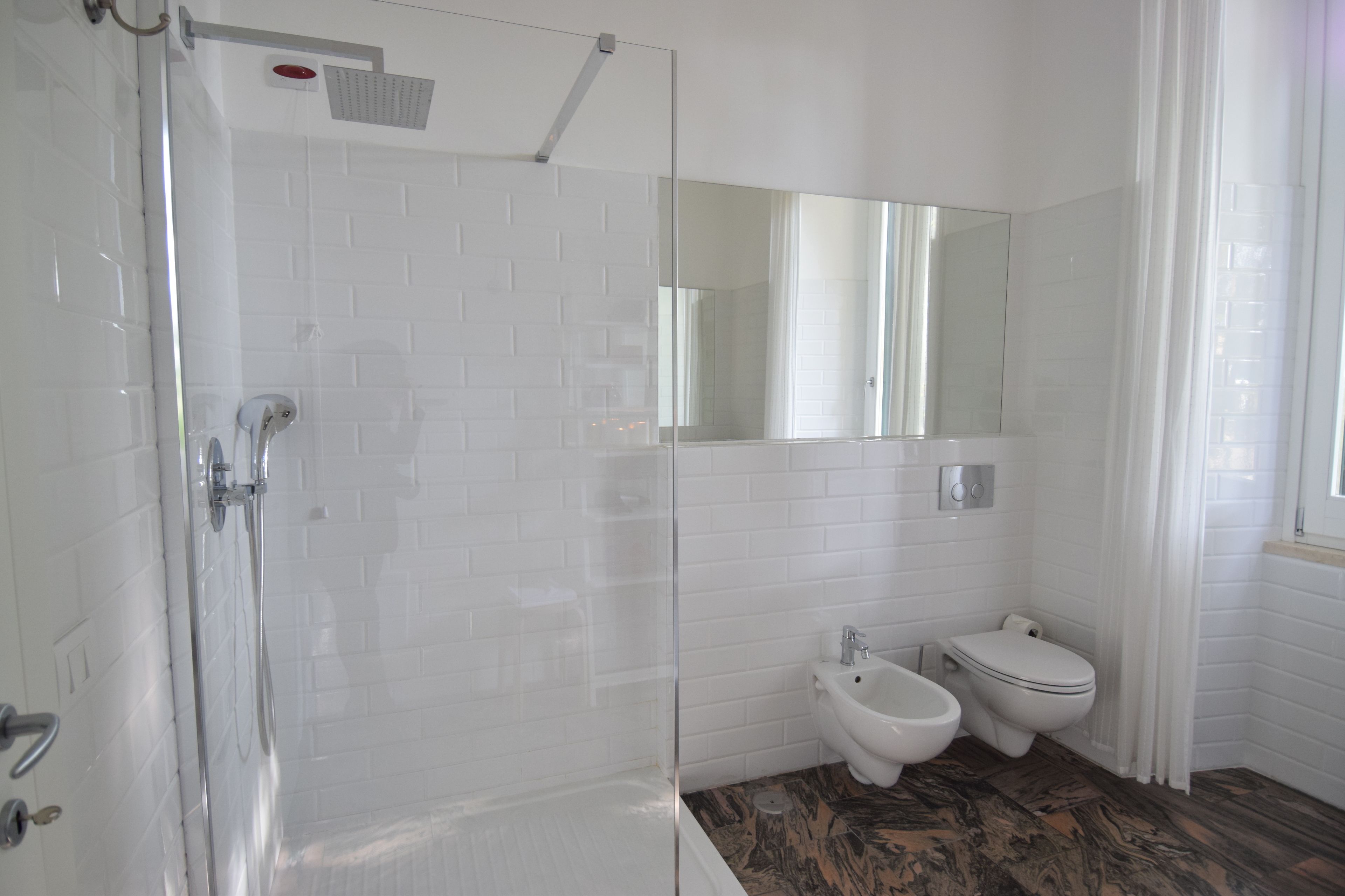 A modern bathroom with a glass shower enclosure, a bidet, and a toilet.