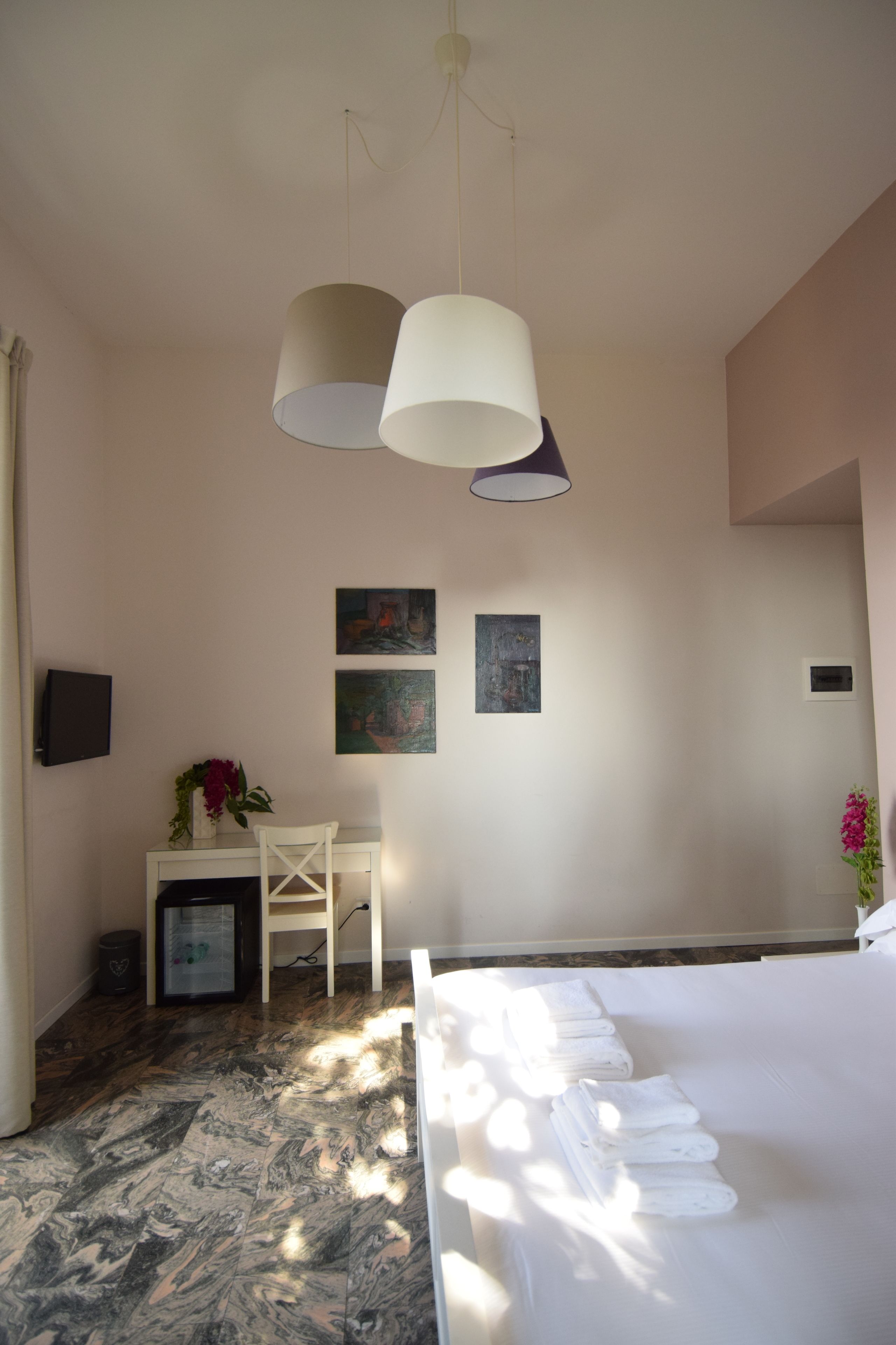 A hotel room with a bed, a desk, a chair, and two wall-mounted lamps.