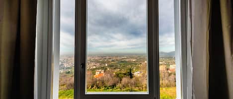 Una ventana con vistas a un paisaje urbano y colinas.