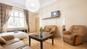 A living room with a sofa, two armchairs, a coffee table, and a TV on the wall. - Premier Apartment near Museum (Prague)