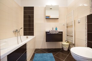 A bathroom with a bathtub, a sink, a toilet, and a towel rack. - Premier Apartment Vysehrad (Prague)