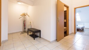 Um corredor com um banco, um cabideiro e uma porta de madeira que dá para um banheiro.