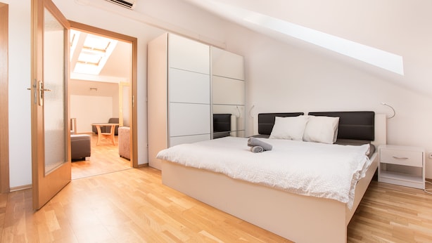 Quarto com cama grande, guarda-roupa e claraboia.