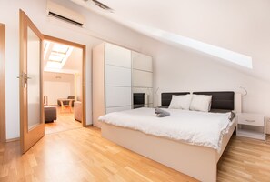 A bedroom with a large bed, a wardrobe, and a skylight. - Premier Apartment Vysehrad (Prague)